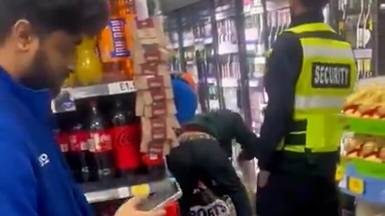 The shocking moment a masked shoplifter brazenly steals alcohol from a Tesco store in London’s Belsize Park as security guards look on.