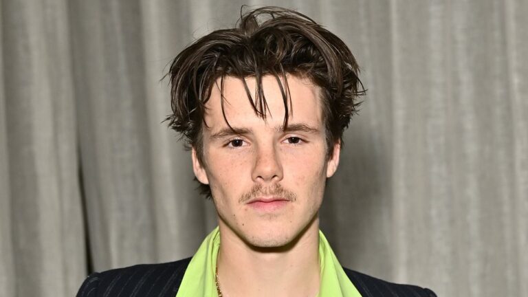 Cruise Beckham opts for a retro look in a green shirt and black pinstripe suit as he attends a star-studded party during London Fashion Week